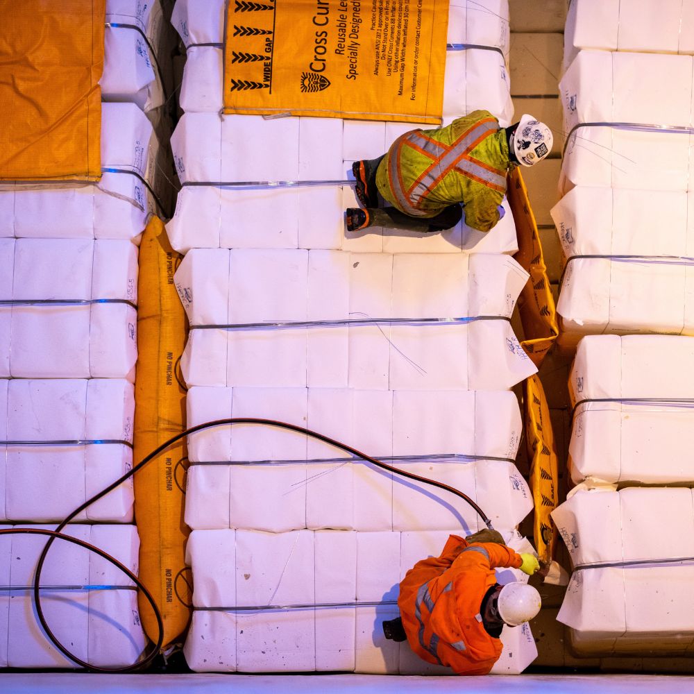 Picture of two men securing cargo in the cargo hold of a open hatch shipping vessel owned by G2 Ocean